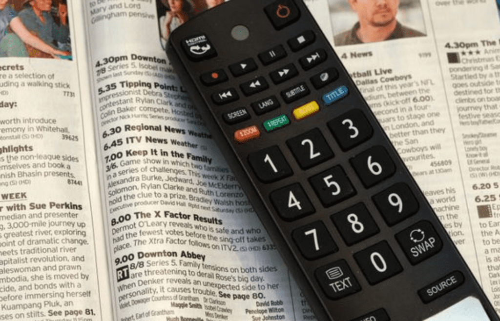 A printed TV Guide magazine next to a remote