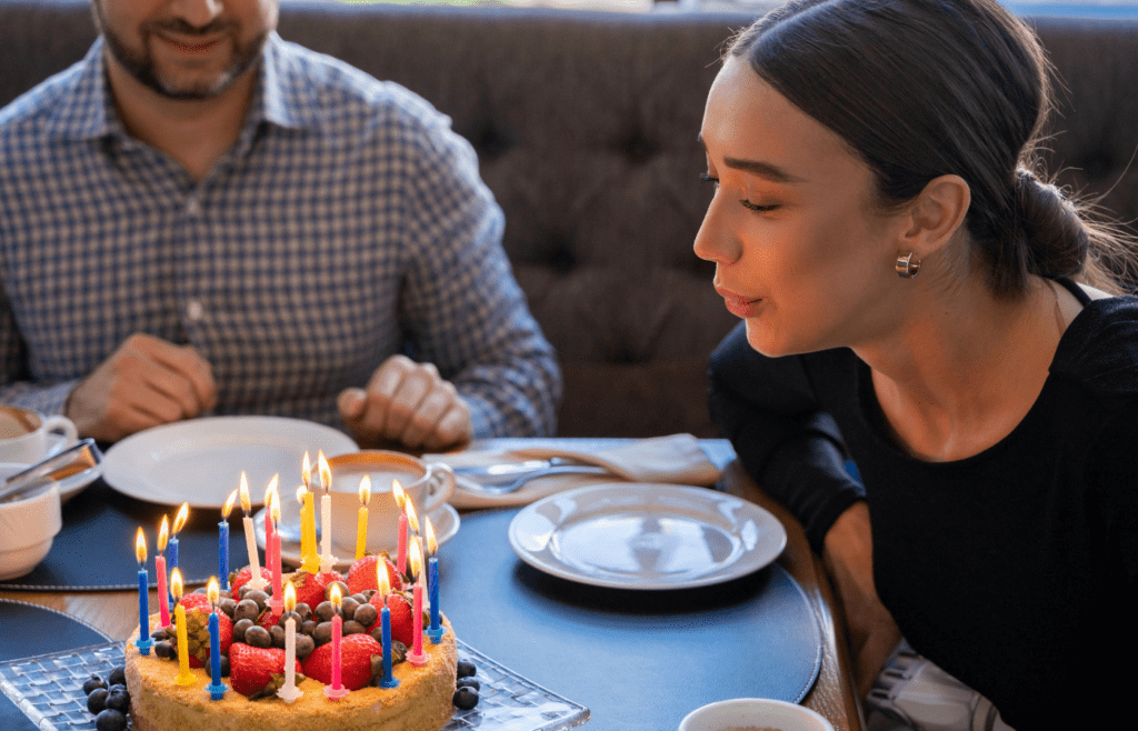 Lady blowing out candles beside her friend