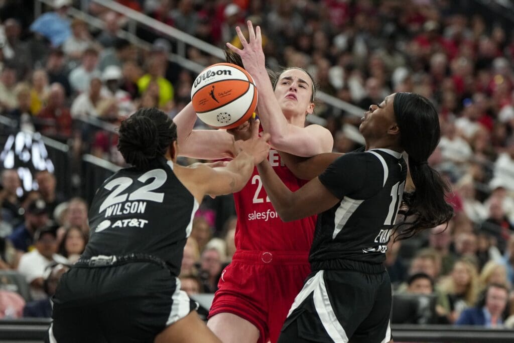 Jun 22, 2025; Las Vegas, Nevada, USA; Indiana Fever guard Caitlin Clark (22) is defended by Las Vegas Aces center A'ja Wilson (22) and guard Dana Evans (11) during the second half of a WNBA basketball game at T-Mobile Arena. Mandatory Credit: Lucas Peltier-Imagn Images