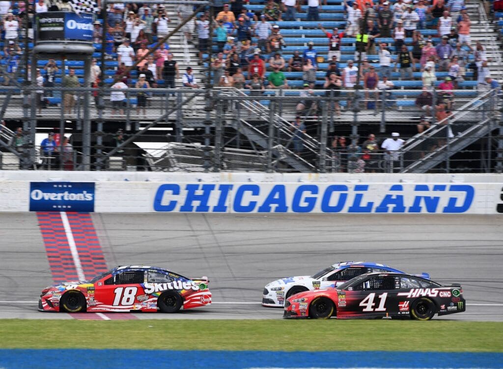 Jul 1, 2018; Joliet, IL, USA; NASCAR Cup Series driver Kyle Busch (18) takes the checkered flag during the Overton's 400 at Chicagoland Speedway. Mandatory Credit: Mike DiNovo-USA TODAY Sports