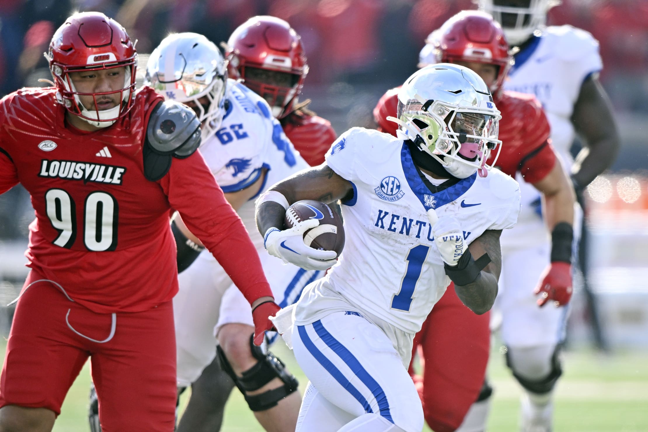 Nov 25, 2023; Louisville, Kentucky, USA; Kentucky Wildcats running back Ray Davis (1) runs the ball past Louisville Cardinals defensive lineman Jermayne Lole (90) during the second half at L&N Federal Credit Union Stadium. Kentucky defeated Louisville 38-31. Mandatory Credit: Jamie Rhodes-USA TODAY Sports