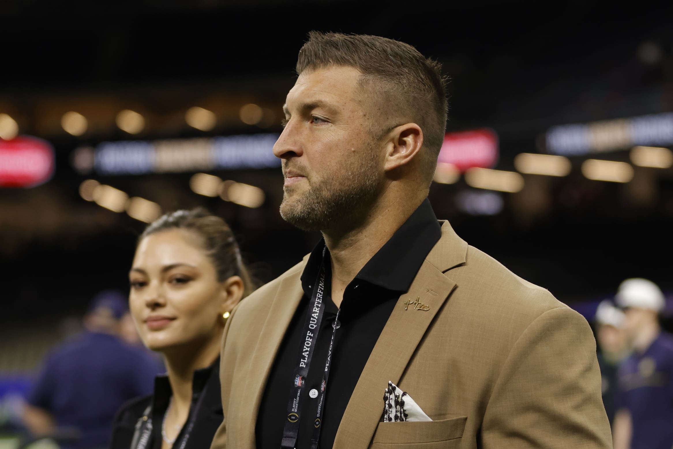 Jan 2, 2025; New Orleans, LA, USA; Tim Tebow (left) and wife Demi-Leigh Tebow (right) walk on the field prior to the game between the Notre Dame Fighting Irish and the Georgia Bulldogs at Caesars Superdome. Mandatory Credit: Amber Searls-Imagn Images