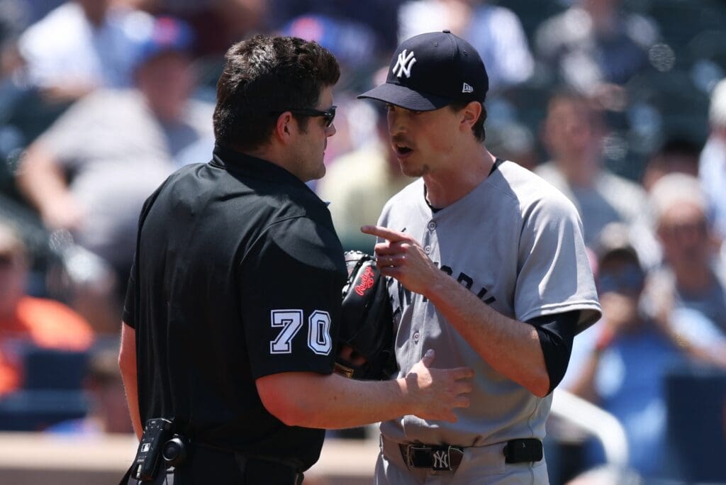 Jul 6, 2025; New York City, New York, USA; New York Yankees starting pitcher Max Fried (54) talks with umpire John Bacon (70) after being called for a clock violation during the first inning against the New York Mets at Citi Field. Mandatory Credit: Vincent Carchietta-Imagn Images