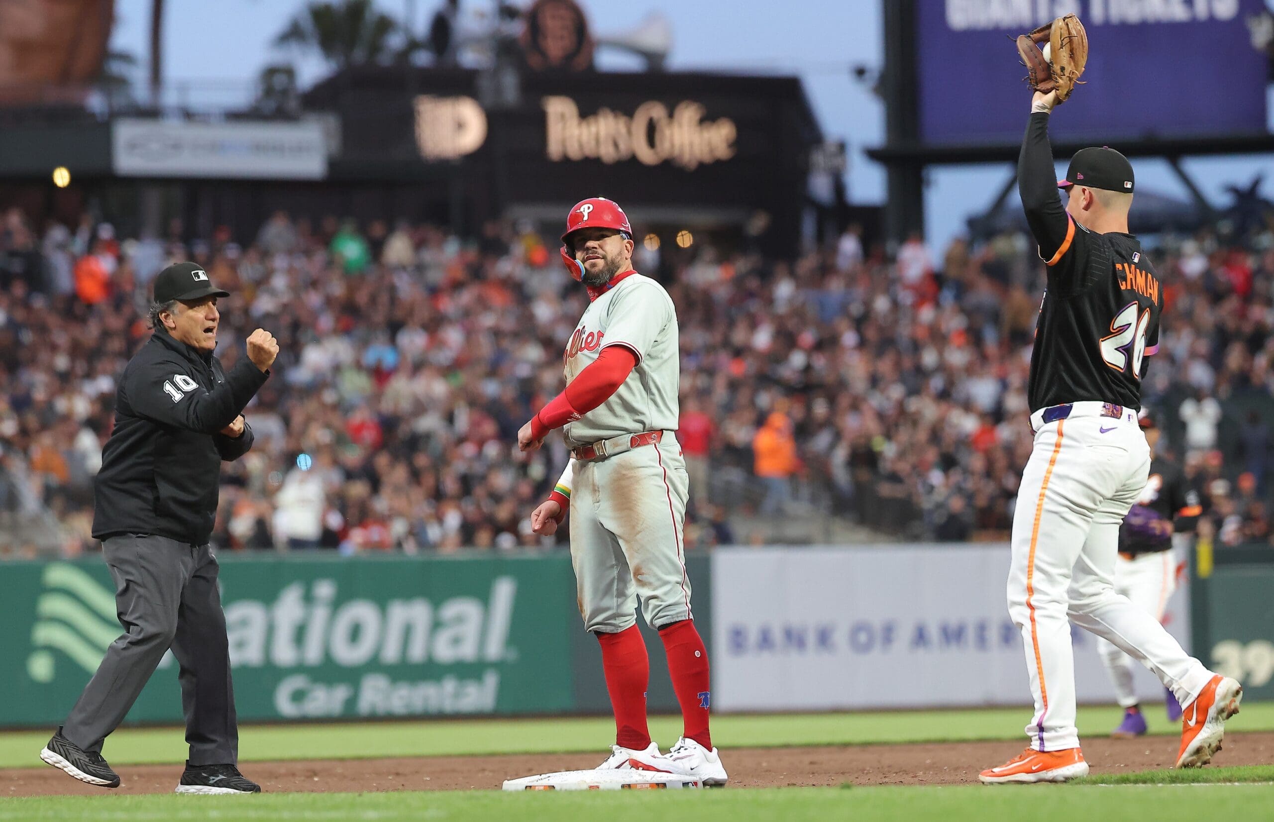 Jul 8, 2025; San Francisco, California, USA; Philadelphia Phillies designated hitter Kyle Schwarber (12) reacts as third base umpire Phil Cuzzi (10) calls him out after trying to steal third base against San Francisco Giants third baseman Matt Chapman (26) during the sixth inning at Oracle Park. Mandatory Credit: Kelley L Cox-Imagn Images