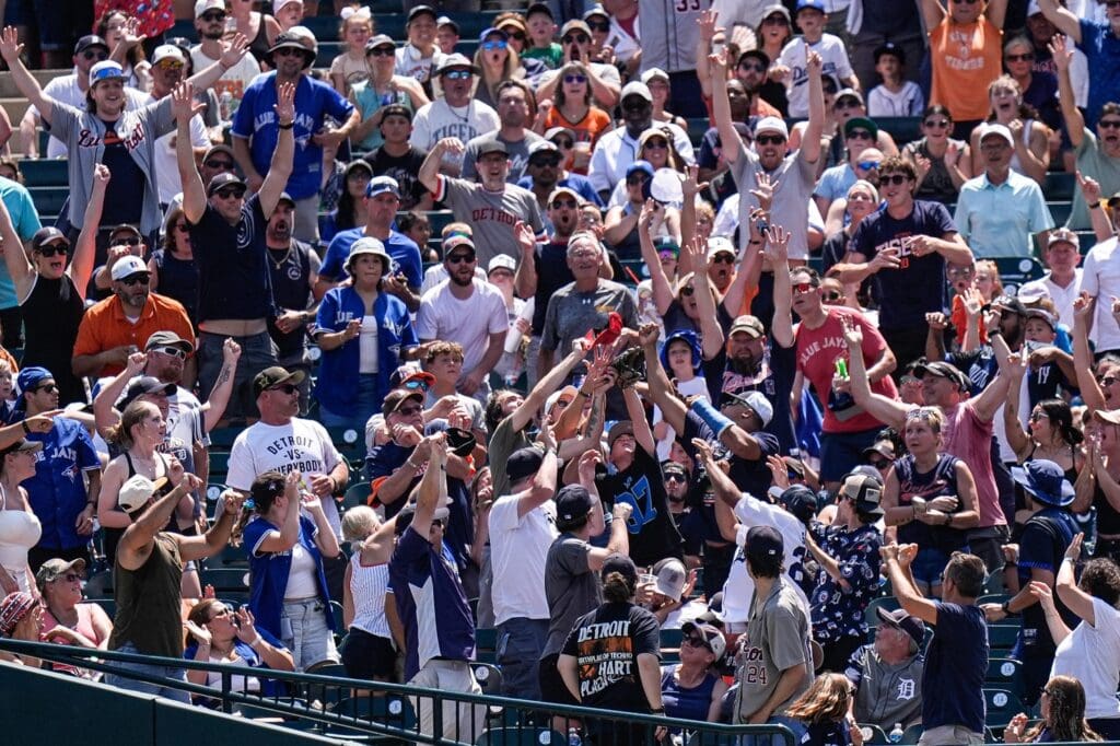 Baseball fans reach for the home run ball from Detroit Tigers second base Gleyber Torres (25) during the third inning against Toronto Blue Jays at Comerica Park in Detroit on Sunday, July 27, 2025.