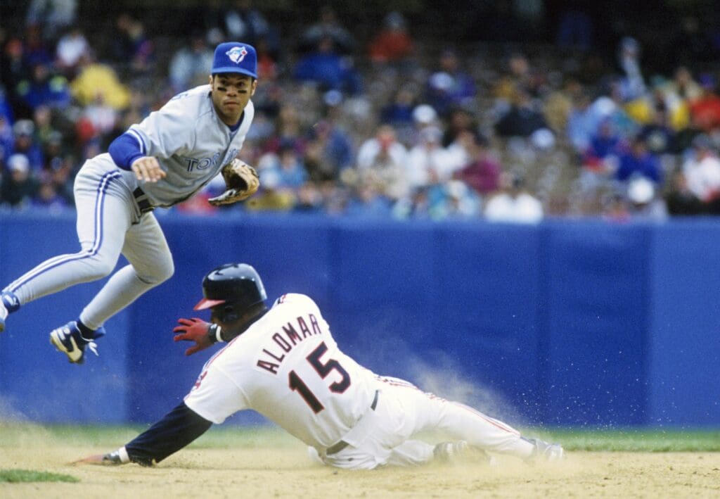 Apr 19, 1993; Cleveland, OH, USA; FILE PHOTO; Toronto Blue Jays infielder Roberto Alomar (left) turns a double play over Cleveland Indians catcher Sandy Alomar (15) at Cleveland Stadium. Mandatory Credit: USA TODAY Sports