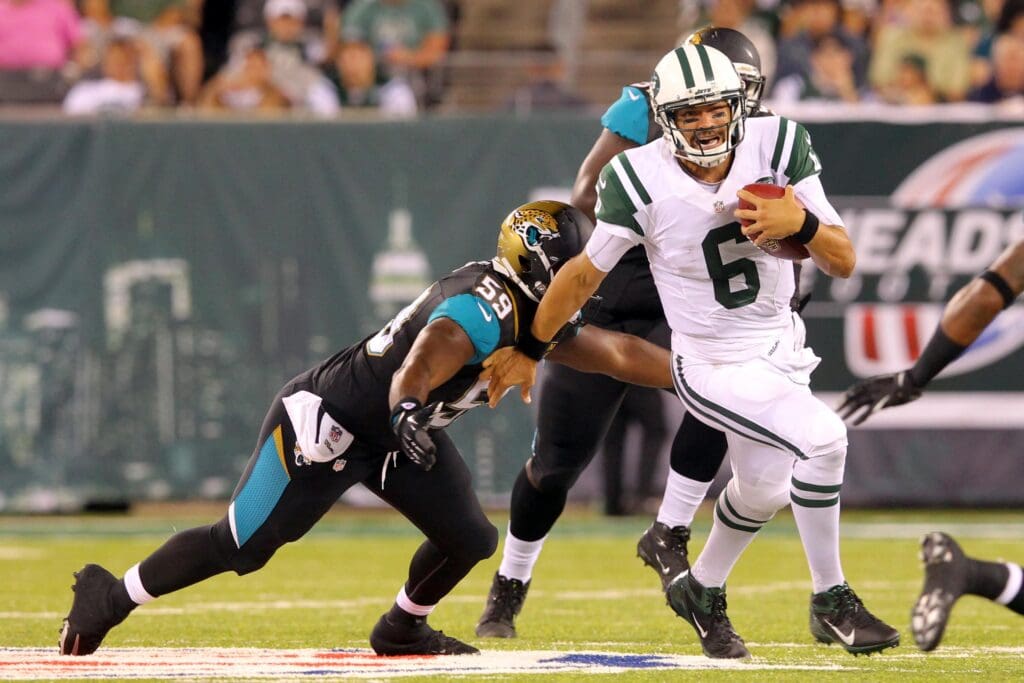 Aug 17, 2013; East Rutherford, NJ, USA; New York Jets quarterback Mark Sanchez (6) runs with the ball while defended by Jacksonville Jaguars defensive end Ryan Davis (59) during the third quarter of a preseason game at MetLife Stadium. The Jets defeated the Jaguars 37-13. Mandatory Credit: Brad Penner-USA TODAY Sports