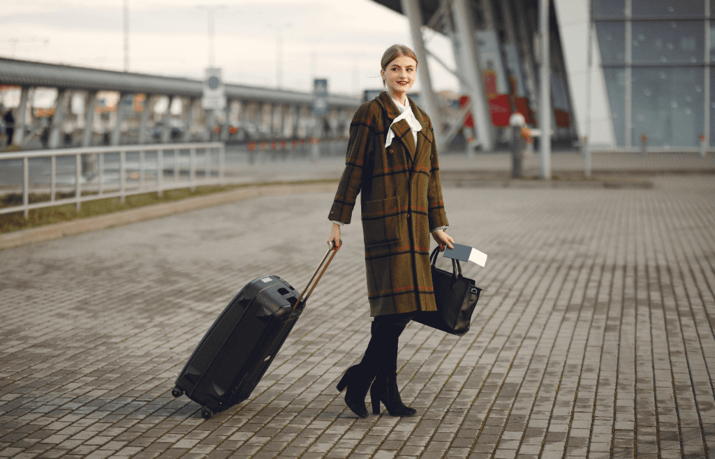 Woman walking with luggage and passport with ticket near contemporary building