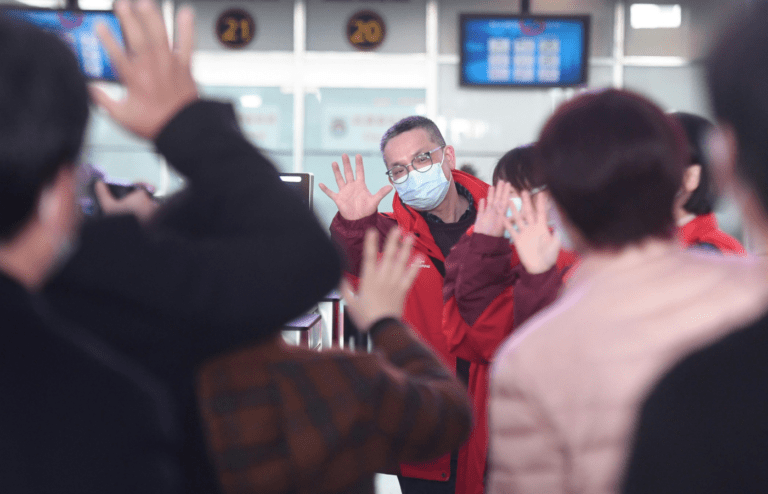 Man in mask waves goodbye at airport gate