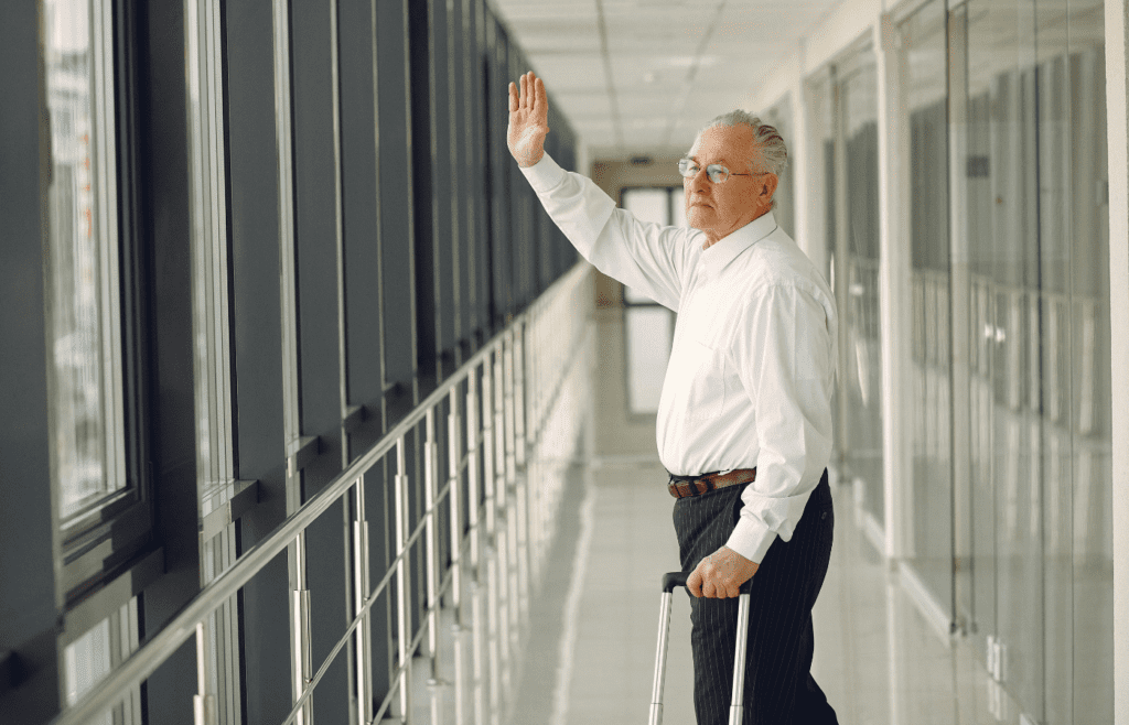 Elderly man waving goodbye near airport security