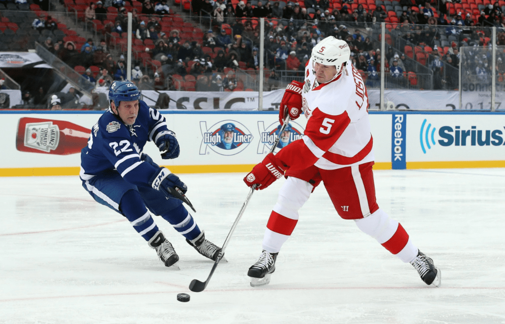Dec 31, 2016; Toronto, ON, Canada; Detroit Red Wings defenseman Nicklas Lidstrom (5) shoots and scores a goal in the second period as Toronto Maple Leafs forward Tiger Williams (22) defends during the 2017 Rogers NHL Centennial Classic Alumni Game at BMO Field. The Red Wings beat the Maple Leafs 4-3. Mandatory Credit: Tom Szczerbowski-Imagn Images