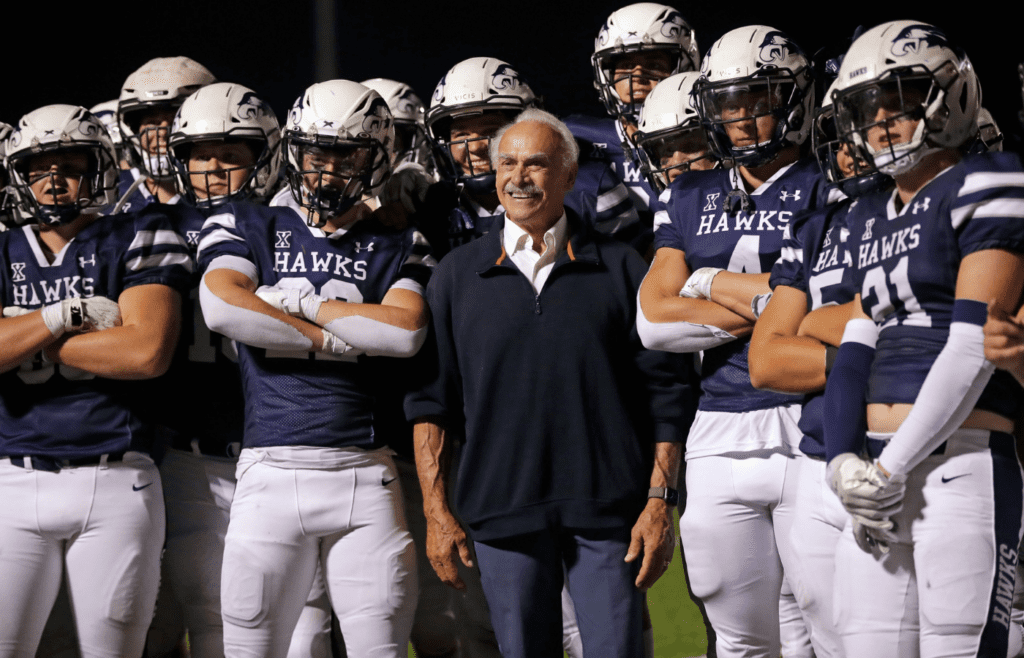 Rocky Bleier poses with Xavier High School football players at halftime during their football game against Valders Friday, August 23, 2024, in Appleton, Wisconsin. Xavier won 56-12.