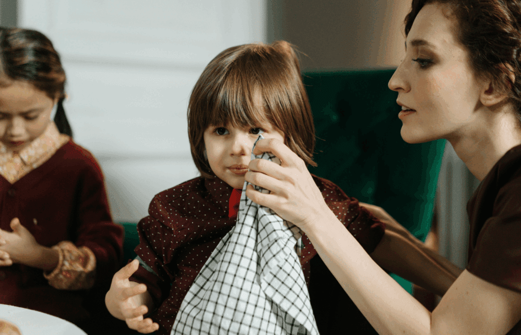 Nanny sitting while wiping child’s face