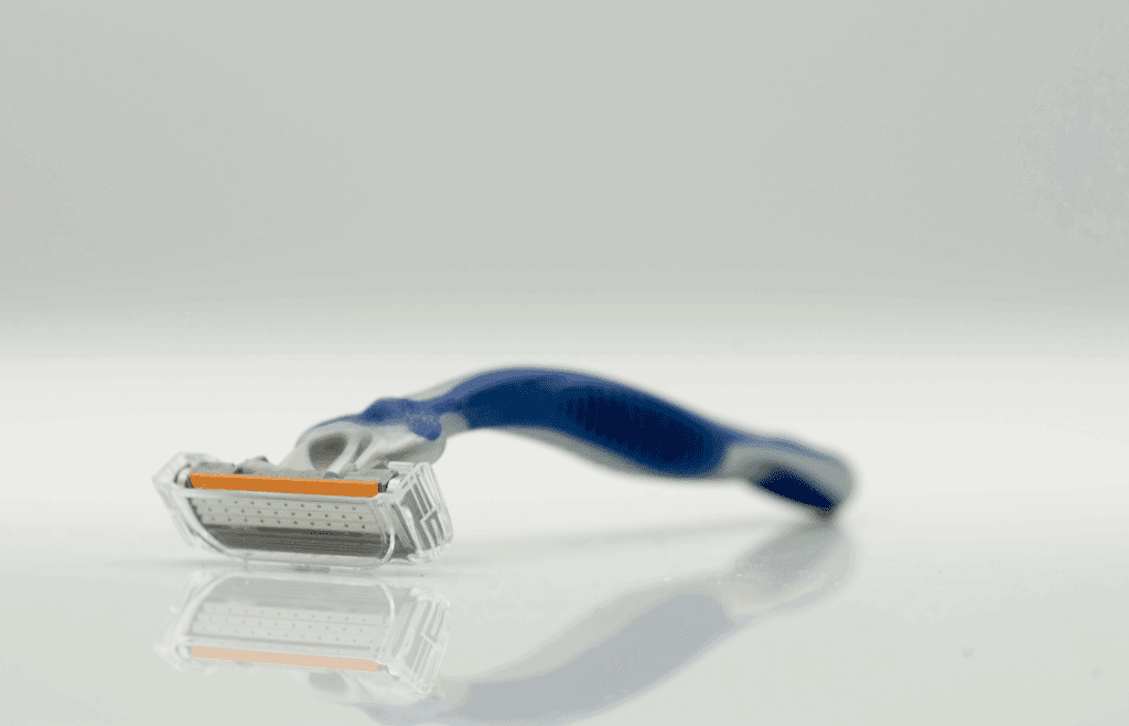 Close-Up Photo of a Blue and Gray Razor on a White Surface