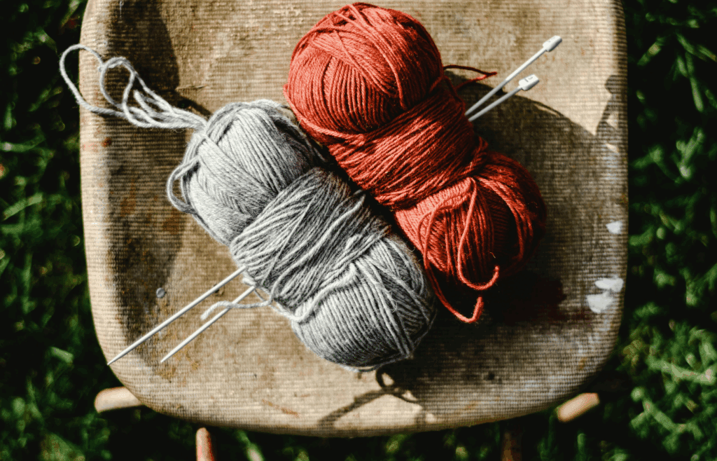 Close-Up Shot of Knitting Needles and Yarn Rolls