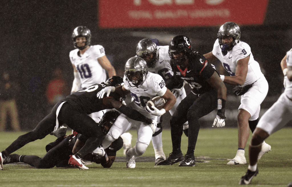 Nov 30, 2024; Cincinnati, Ohio, USA; TCU Horned Frogs running back Jeremy Payne (26) is tackled by Cincinnati Bearcats linebacker Jiquan Sanks (9) in the third quarter at Nippert Stadium. Mandatory Credit: Albert Cesare/USA TODAY Network via Imagn Images