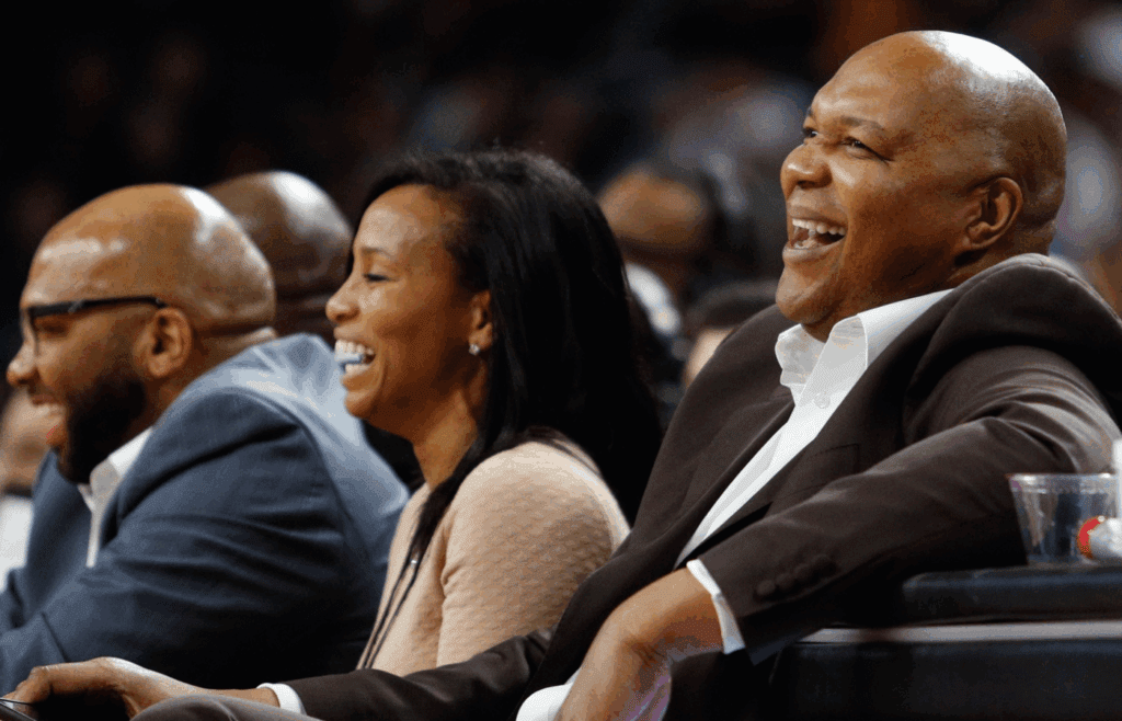 Feb 15, 2017; Auburn Hills, MI, USA; Former player Derrick Coleman (right) laughs with his wife Gina Coleman (middle) during the second quarter in the game between the Detroit Pistons and the Dallas Mavericks at The Palace of Auburn Hills. Pistons won 98-91. Mandatory Credit: Raj Mehta-Imagn Images