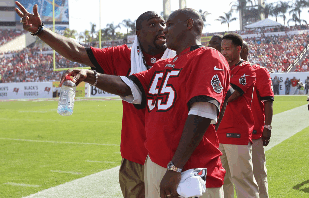 December 9, 2012; Tampa, FL, USA; Tampa Bay Buccaneers former player Warren Sapp (left) and former player Derrick Brooks talk on the sidelines during the first half against the Philadelphia Eagles at Raymond James Stadium.Former players of the 2002 super bowl championship team came back to celebrate their 10th anniversary. Mandatory Credit: Kim Klement-Imagn Images