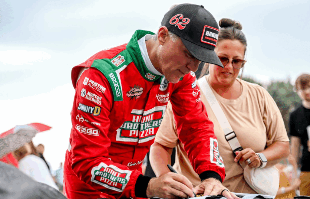 Former NASCAR Cup Series champion Kevin Harvick signs items for fans during an autograph session before the 13th annual Masters of the Pros 200 race on Wednesday, July 16, 2025, at the Owosso Speedway. Harvick and his 13-year-old son Keelan competed against each other in the race later in the night.