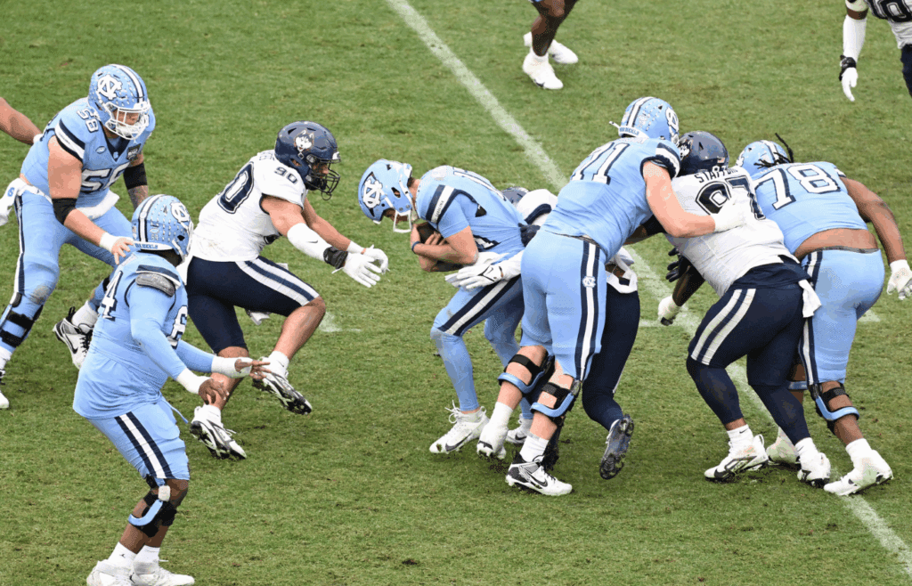 Dec 28, 2024; Boston, MA, USA; Connecticut Huskies defensive lineman Pryce Yates (90) and linebacker Aaron Key (5) sack North Carolina Tar Heels quarterback Michael Merdinger (17) during the second half at Fenway Park. Mandatory Credit: Eric Canha-Imagn Images