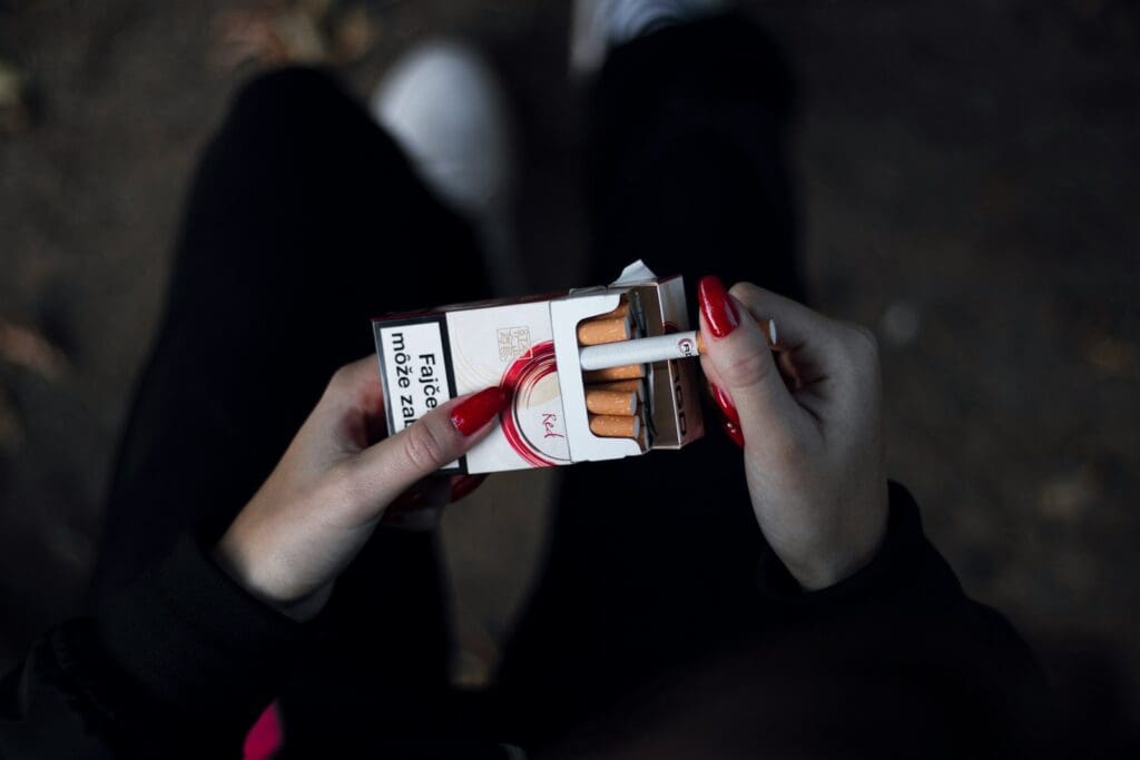 person holding cigarette out of the pack