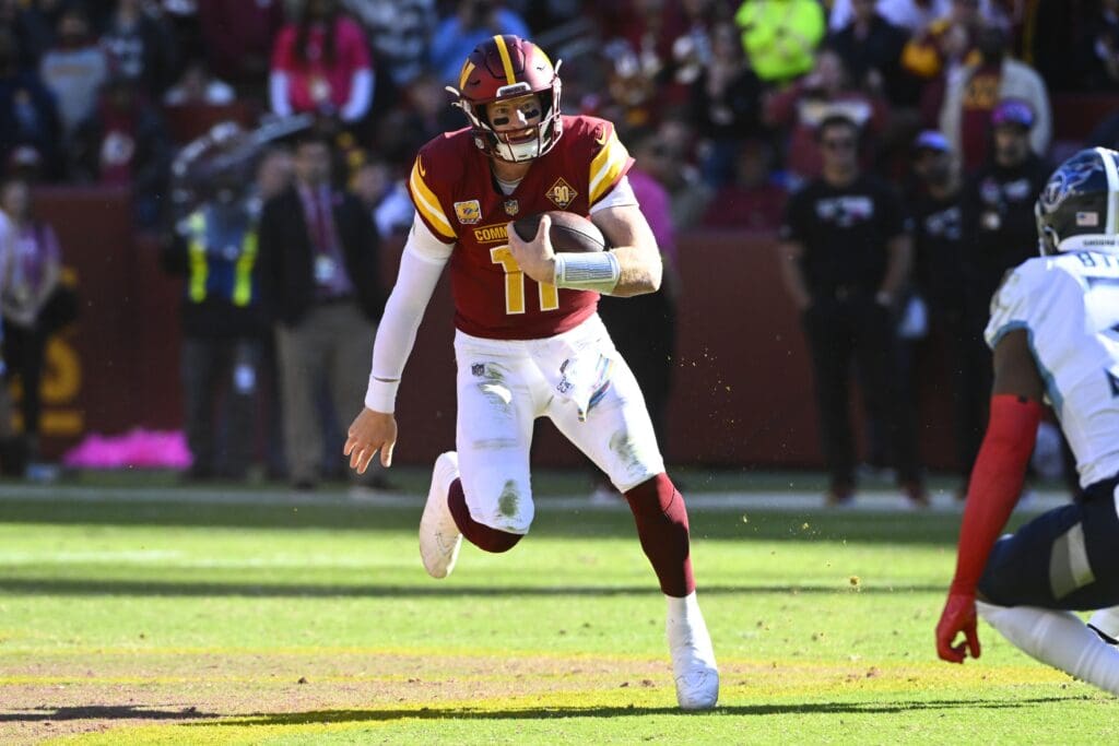 Oct 9, 2022; Landover, Maryland, USA; Washington Commanders quarterback Carson Wentz (11) runs for a first down against the Tennessee Titans during the second half at FedExField. Mandatory Credit: Brad Mills-USA TODAY Sports