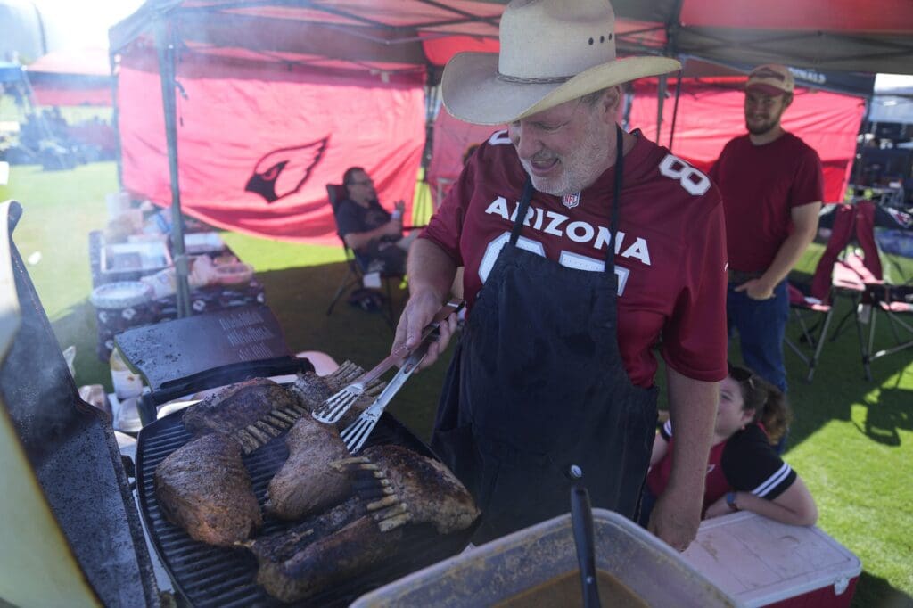 John Fowler cooks racks of lamb and tri-tip steak while tailgating before the Los Angeles Rams play against the Arizona Cardinals at State Farm Stadium on Sept. 15, 2024.