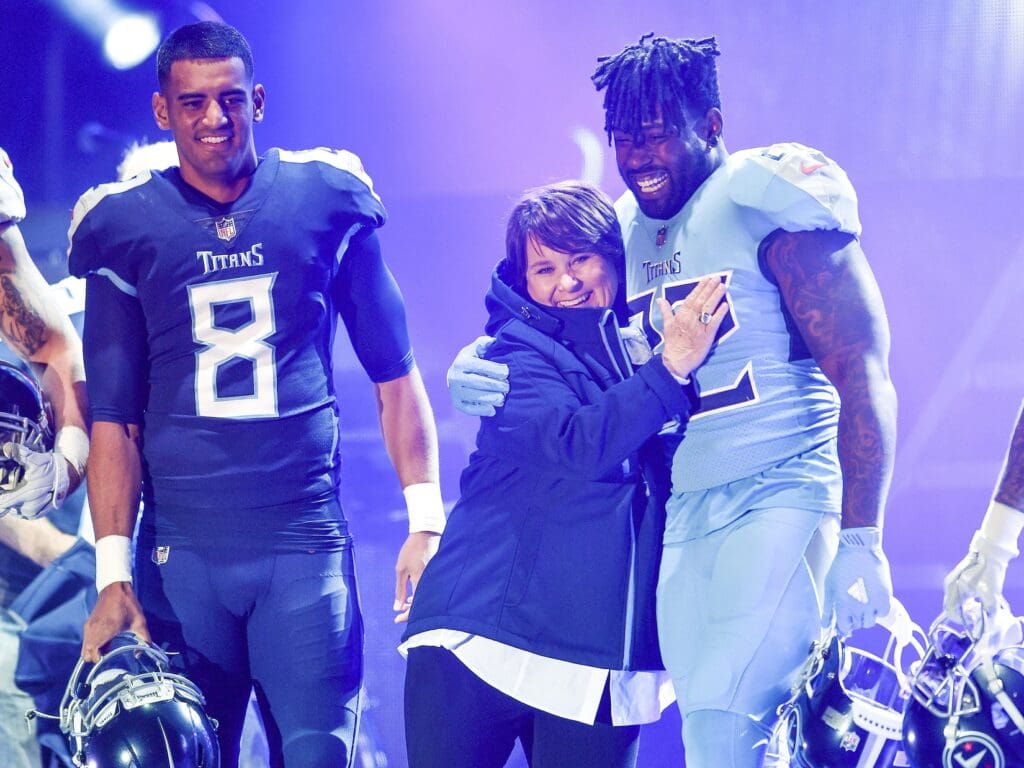 Tennessee Titans owner Amy Adams Strunk hugs Tennessee Titans tight end Delanie Walker (82) as quarterback Marcus Mariota (8) looks on during the Titans uniform reveal event held on Lower Broadway inNashville on April 4, 2018.