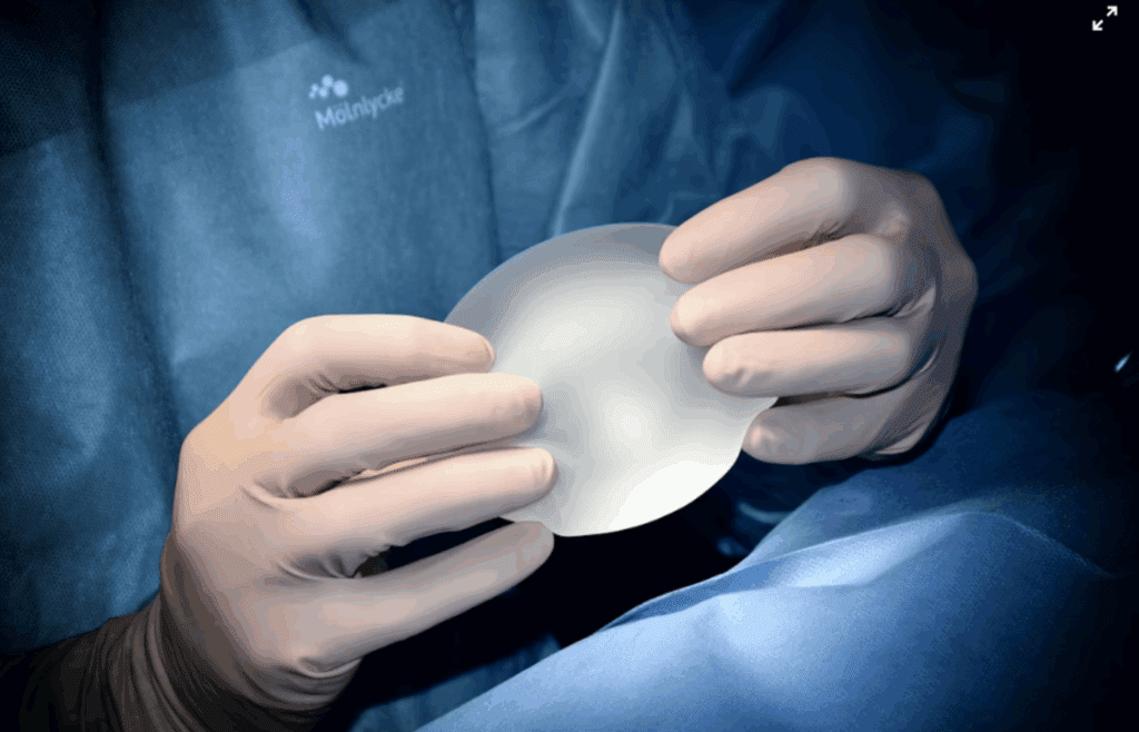Surgeon holding silicone breast implant under light